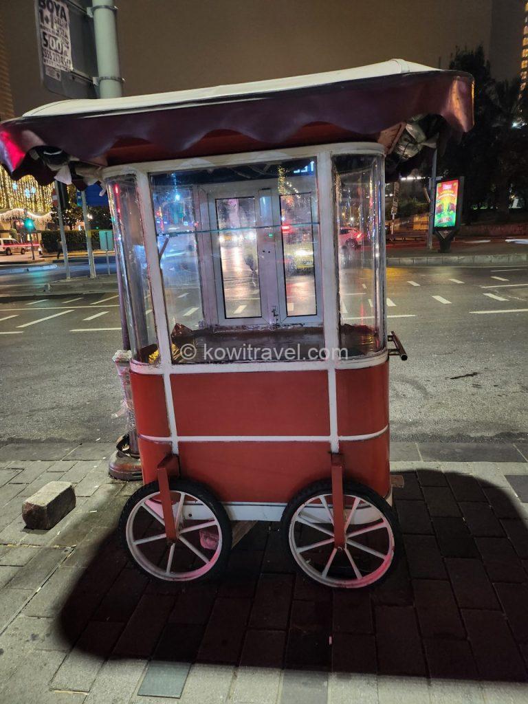 A mobile street food stool selling Turkey's national snack, "Simit," and roasted chestnuts. Simit is a bread made by shaping dough into a circle, sprinkling it with sesame seeds, and baking it; it can be commonly seen on any street.