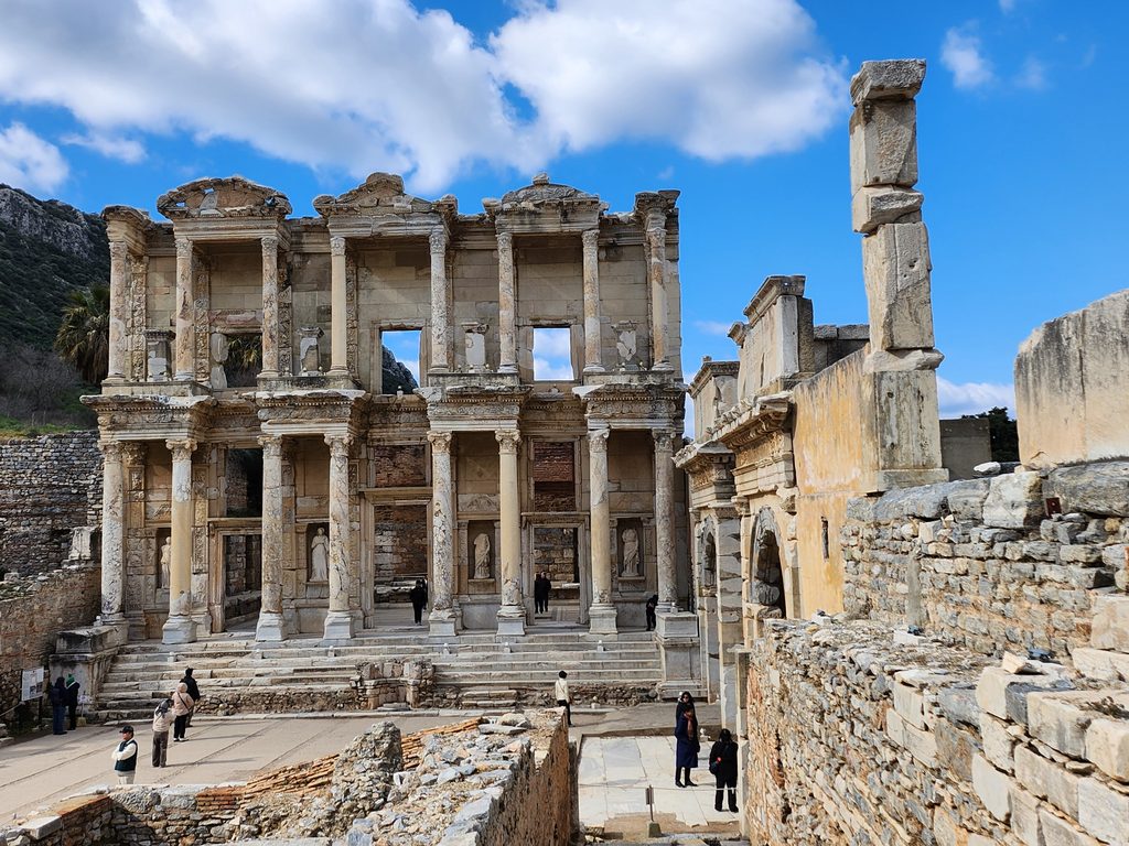 켈수스 도서관 (Library of Celsus)의 웅장한 2층짜리 파사드(전면부)가 담긴 대표적인 정면 전경. 서기 2세기 로마의 소아시아 총독이었던 켈수스를 기리기 위해 그의 아들이 건립한 건축물로, 고대 세계 3대 도서관 중 하나라는 명성에 걸맞은 압도적인 정교함을 자랑합니다. 오른쪽에 보이는 아치형 문은 아우구스투스 황제 시절 해방된 노예들이 황제 가문을 위해 세운 마제우스와 미트리다테스의 문이라고 합니다.
