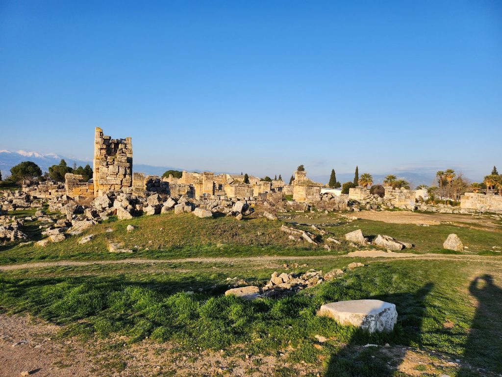 Panoramic view of the fallen stone towers and marble foundations scattered across the green lawns of the Agora