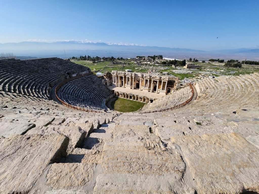 A majestic view of the Roman theater, the crowning jewel of the Hierapolis open-air archaeological site. Standing at the very top center of the seating area and looking down, one is overwhelmed by a sense of grandeur and a dizzying feeling of openness that sends shivers down the spine.