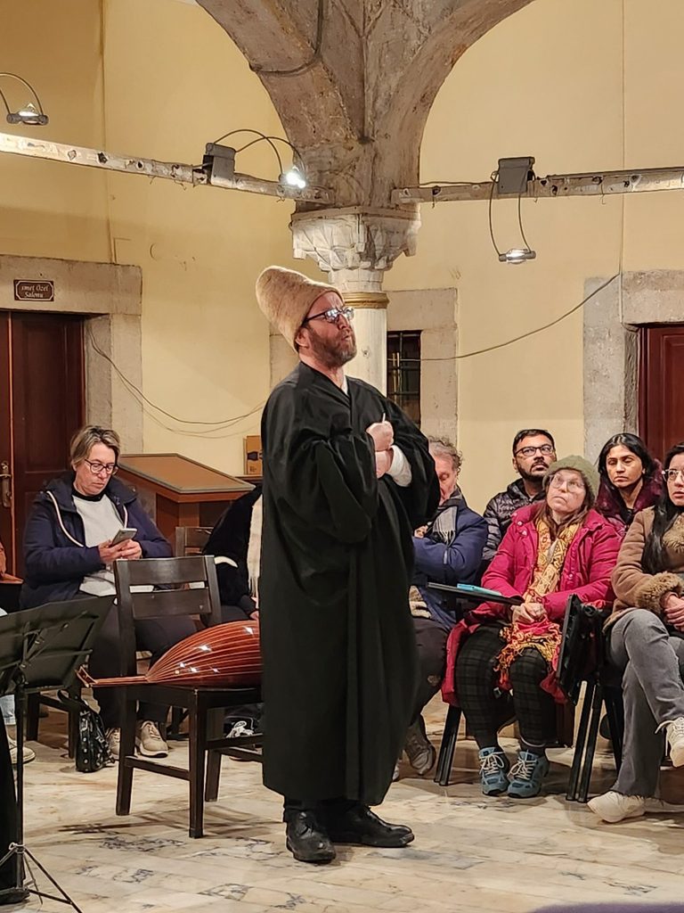 Postnişin or Sheikh/Şeyh: This refers to the leader or master of ceremonies who oversees and conducts the rituals during the Turkish Sema performance, a religious ceremony of the Islamic mysticism (Sufism) order.
